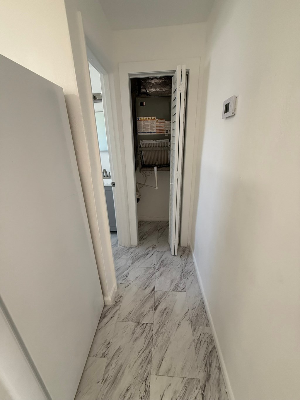A hallway with a marble floor and white walls.