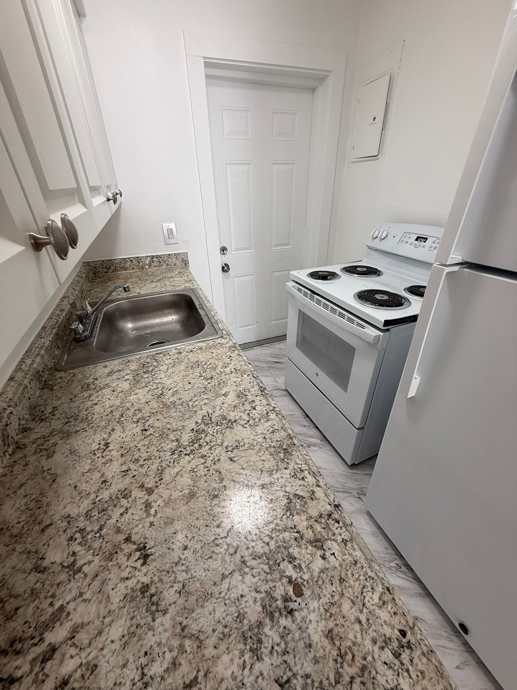 A kitchen with granite countertops and white appliances.