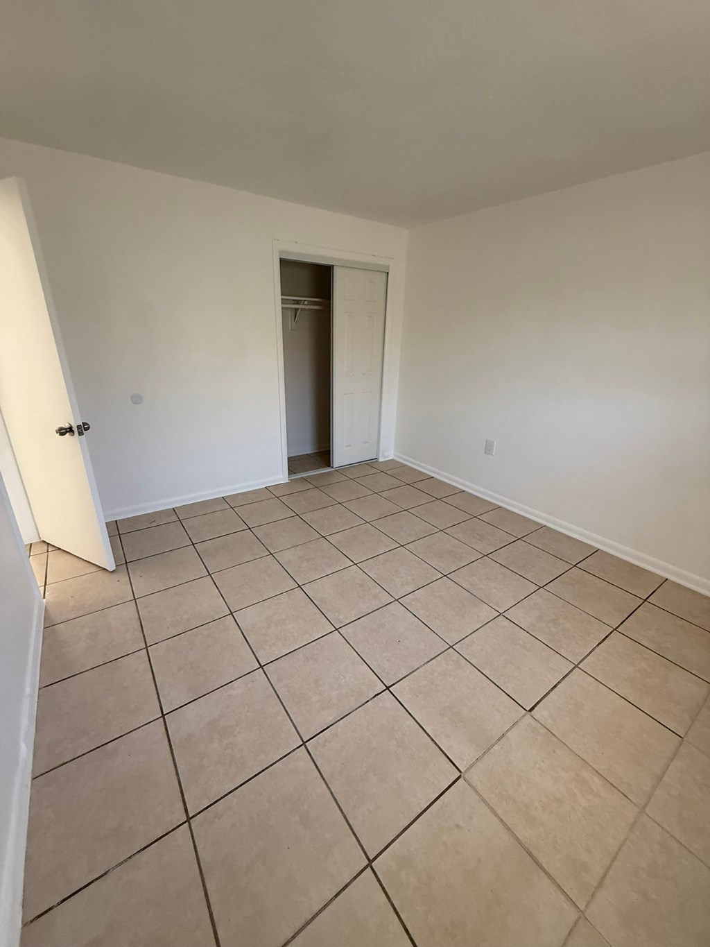 A room with a tiled floor and a door in the background.
