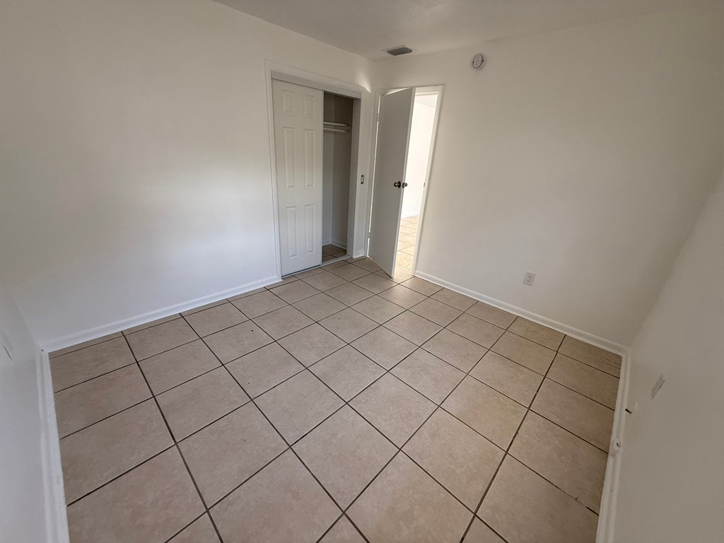 A room with tiled flooring and two doors.