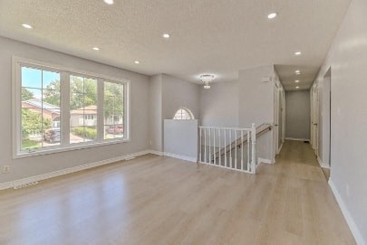 an empty living room with a staircase and a large window