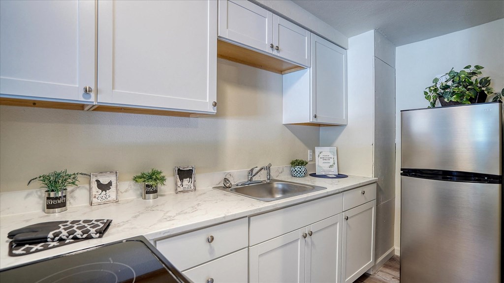 A kitchen with white cabinets and a stainless steel refrigerator.