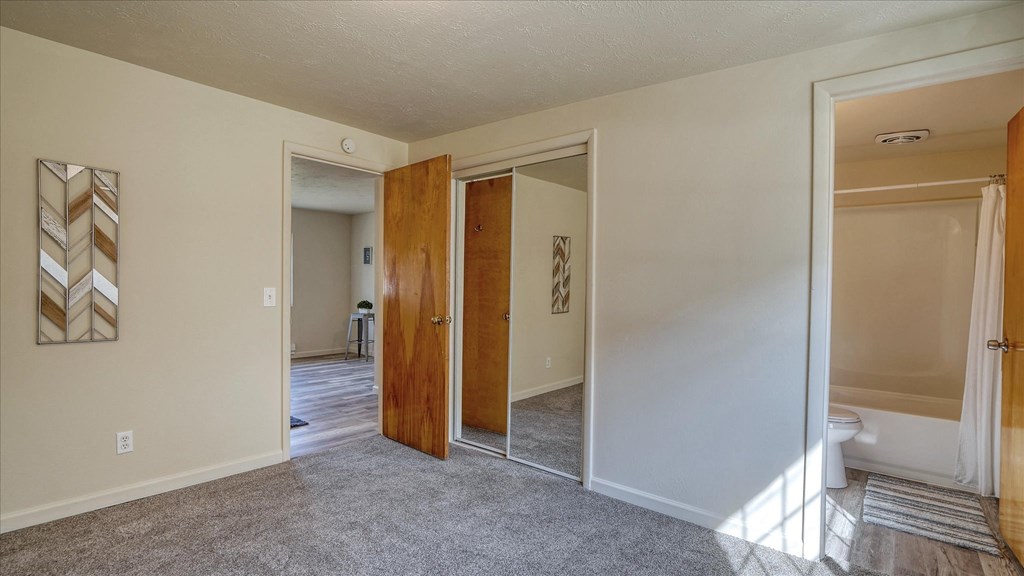 A room with a wooden door and a white wall with a picture on it.