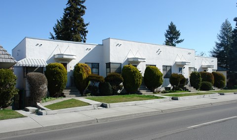 A row of white houses with green bushes in front.