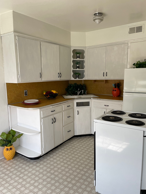 A kitchen with white cabinets and a white refrigerator.