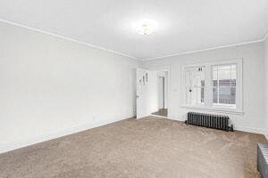an empty living room with a window and a radiator