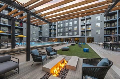 an outdoor lounge area with a fire pit and a pool in an apartment building