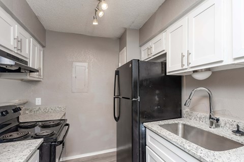 a kitchen with white cabinets and a black refrigerator