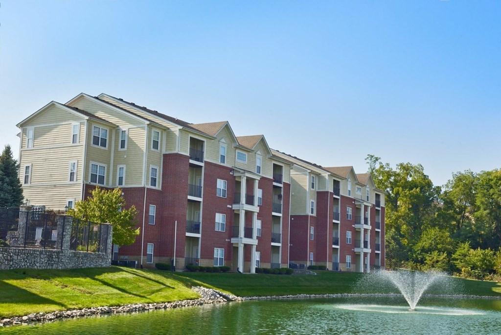 a fountain in a pond in front of an apartment building