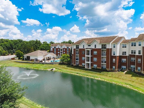 a fountain in a pond in front of an apartment building