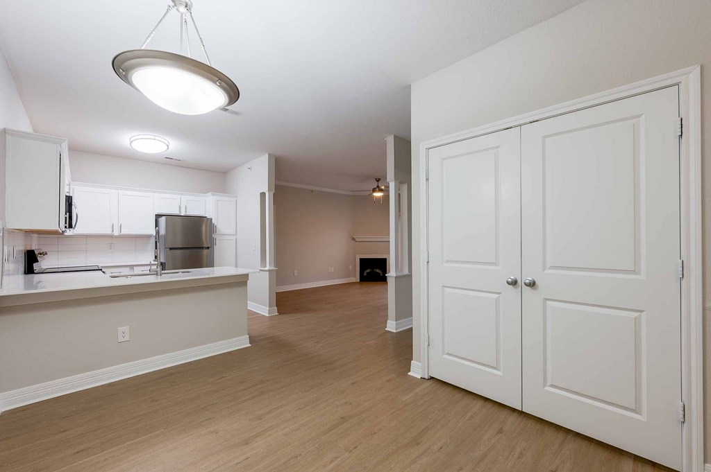 A kitchen with white cabinets and a wooden floor.