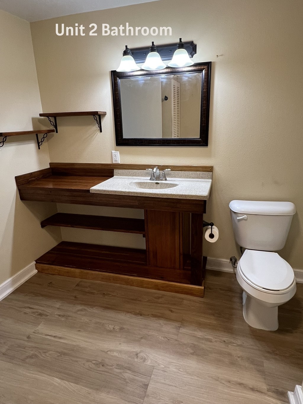 A bathroom with a toilet, sink, and mirror.