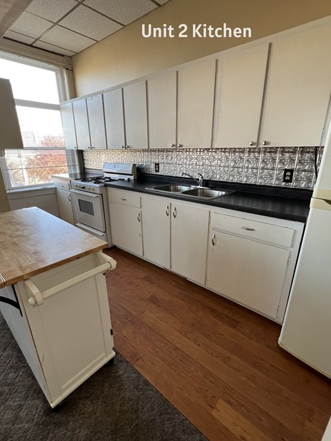 A kitchen with white cabinets and a wooden island.