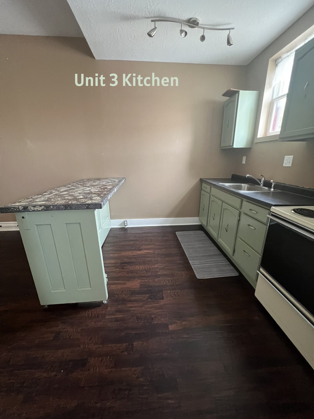 A kitchen with brown floors and white cabinets.