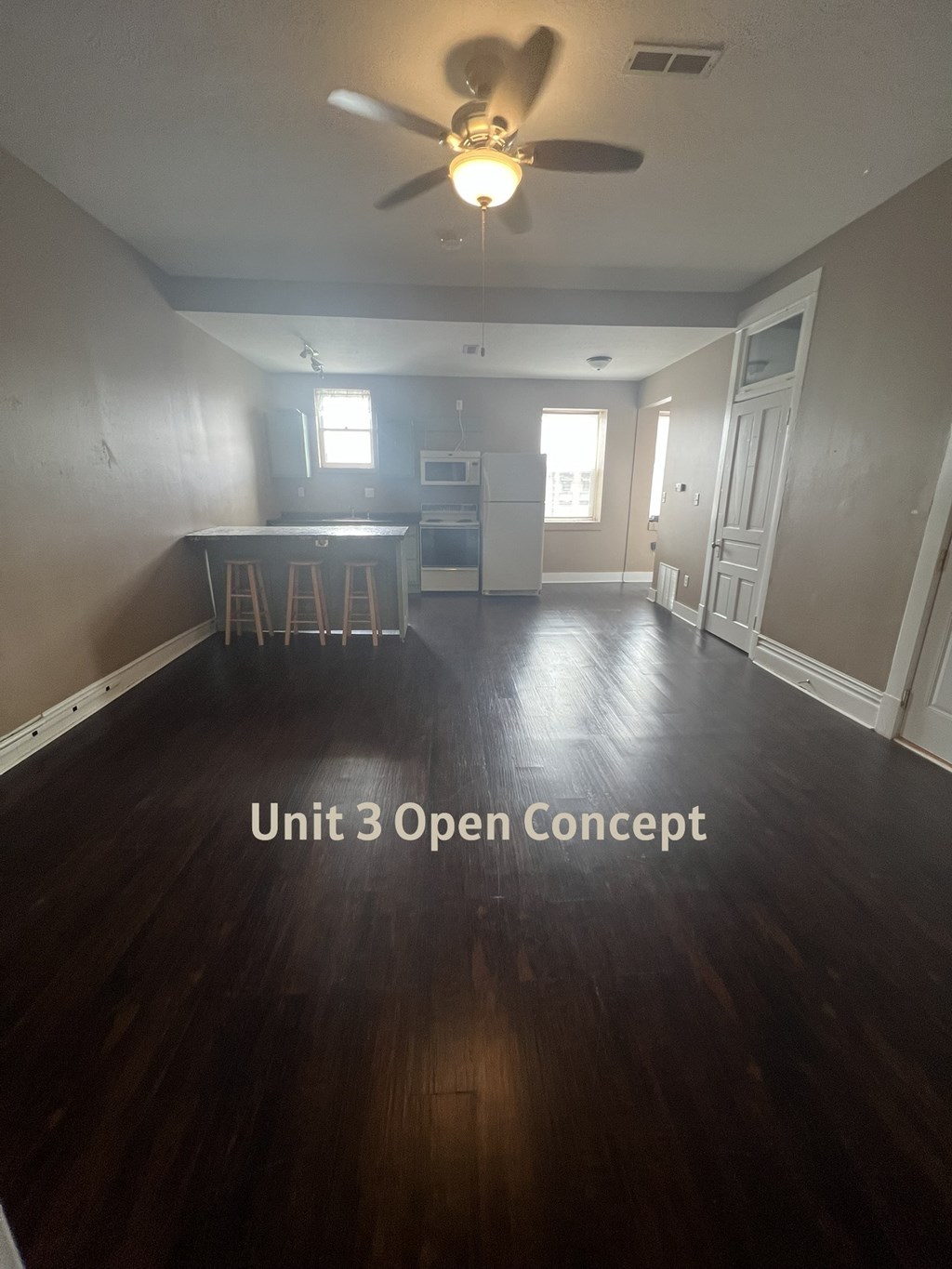 A spacious room with a bar area and a ceiling fan.