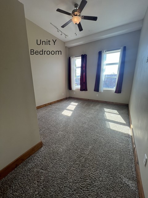 A bedroom with a carpeted floor and a ceiling fan.