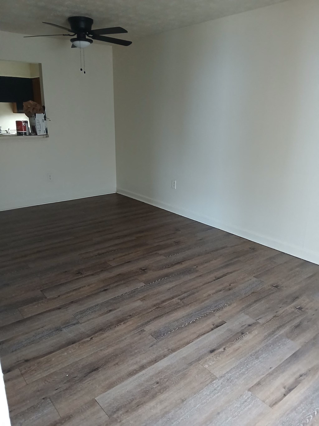 A room with a ceiling fan and wooden flooring.
