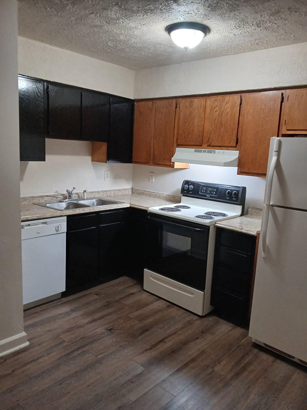 A kitchen with black cabinets and white appliances.