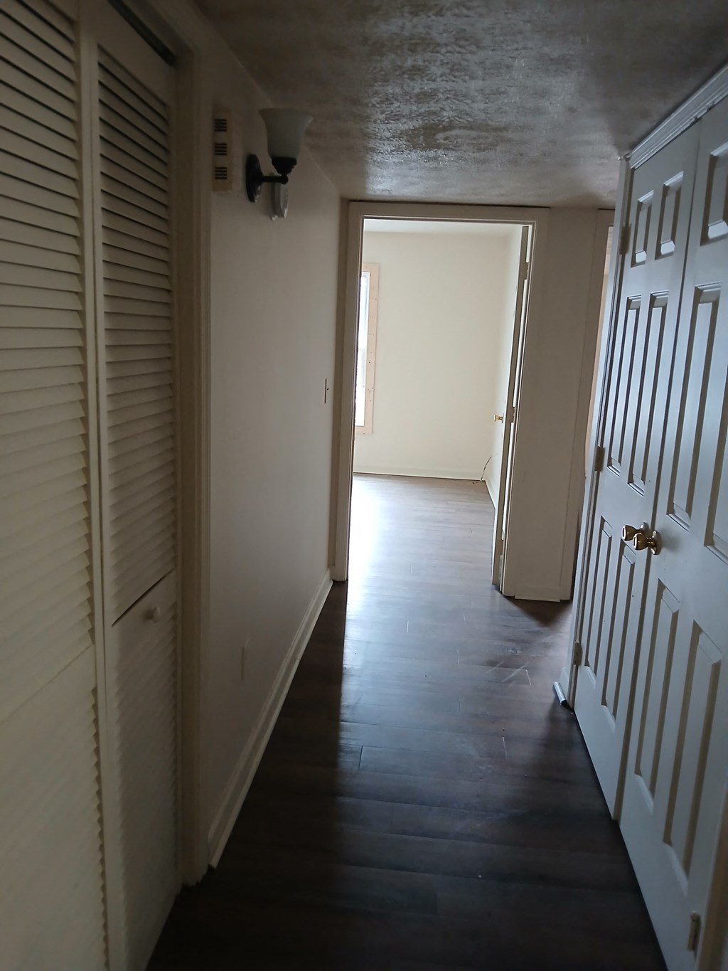 A hallway with white doors and a light on the wall.