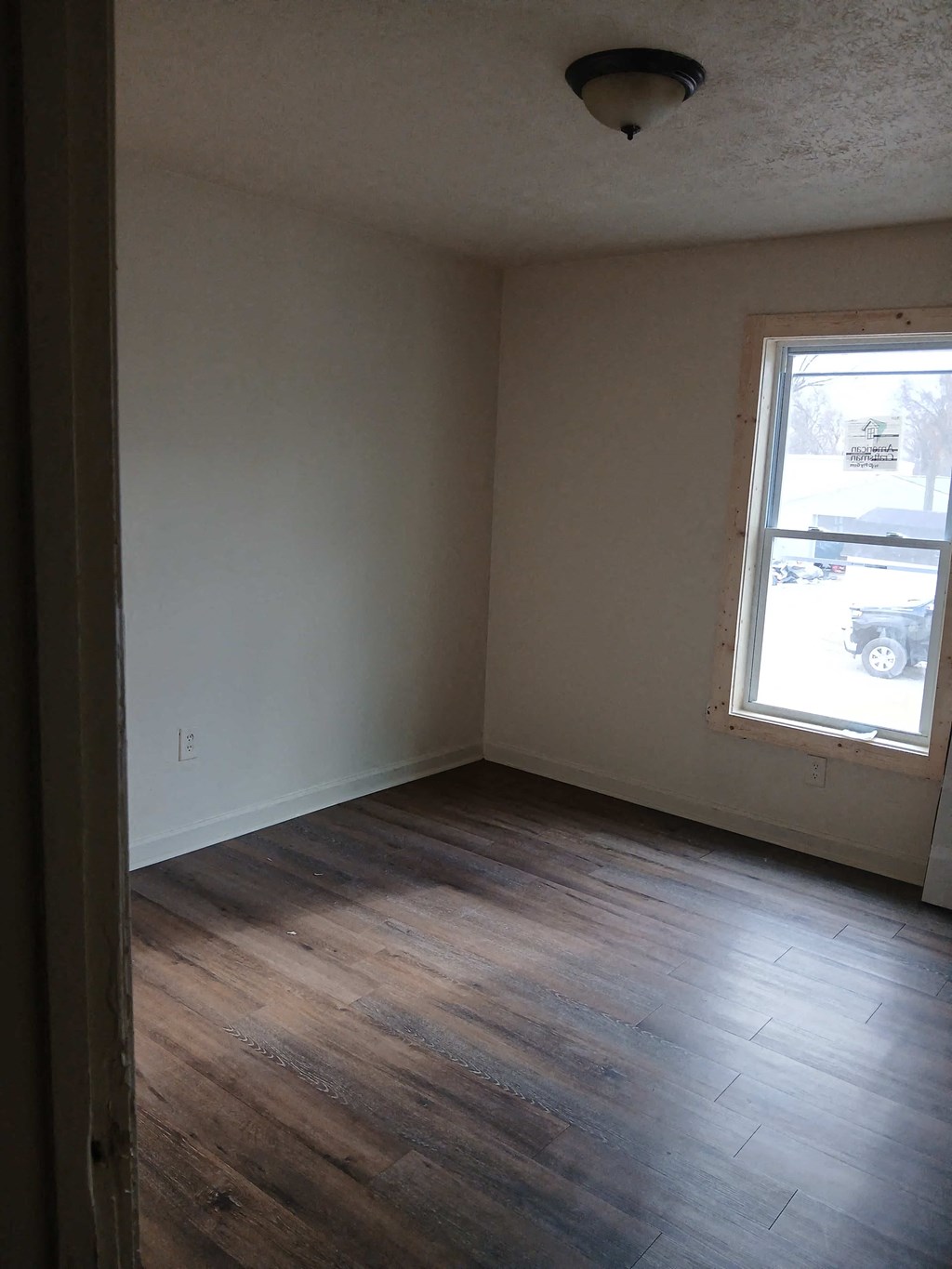 A room with a window and wooden floors.