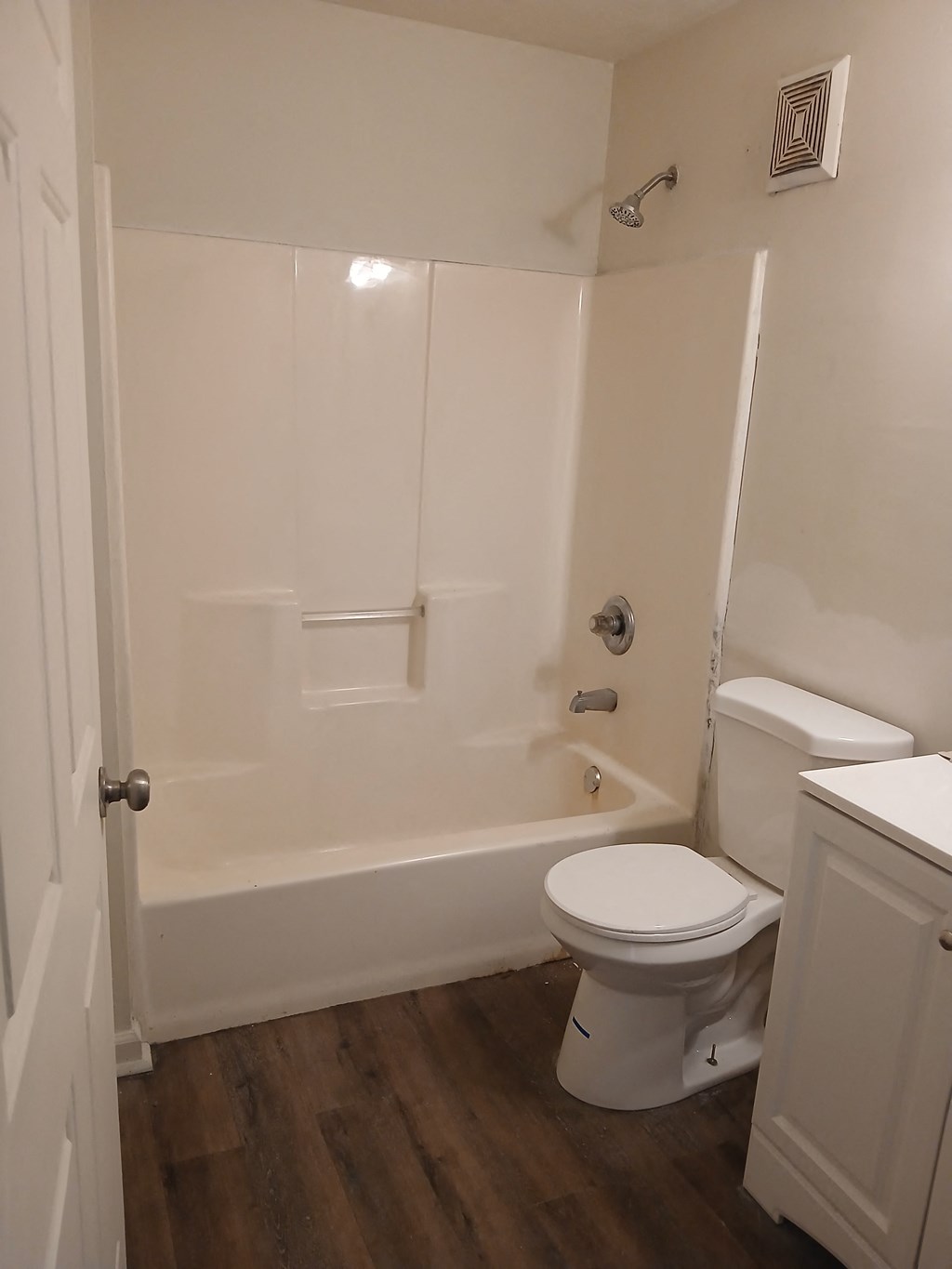 A white toilet sits in a bathroom next to a bathtub.