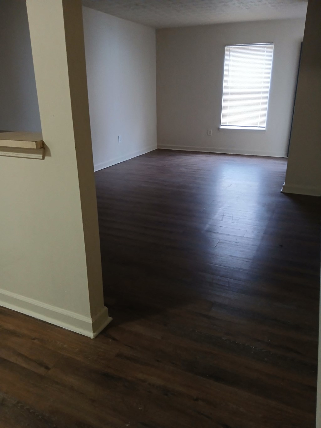 A room with wooden floors and a window with blinds.