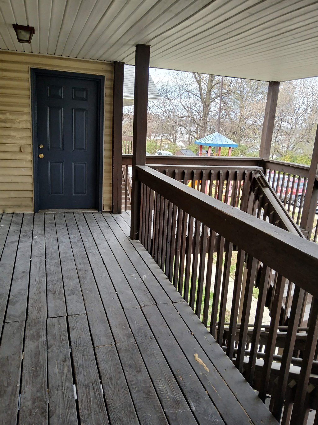 A wooden deck with a black door and railing.