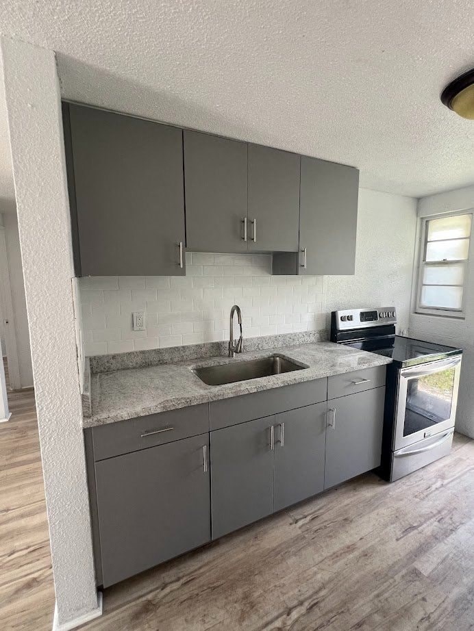 A kitchen with grey cabinets and a granite countertop.