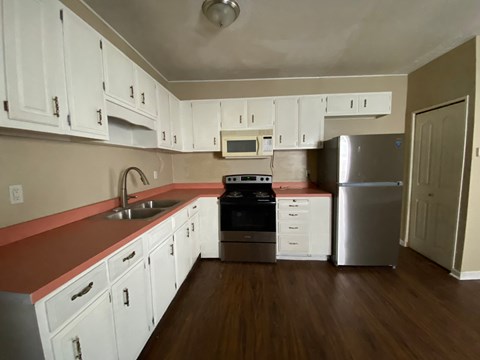 A kitchen with white cabinets and a red counter.
