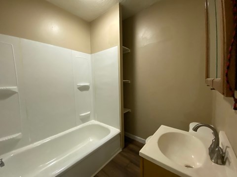 A white bathroom with a bathtub, sink, and towel rack.