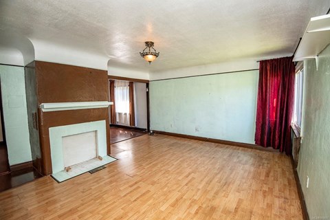 an empty living room with a fireplace and a wooden floor