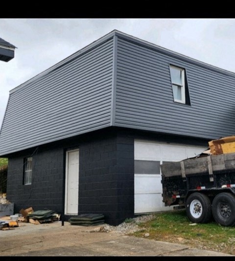 A black house with a white door and a truck parked in front.