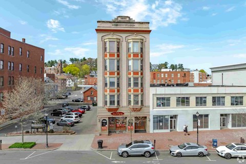 A tall building with a red and white striped facade stands in the middle of a parking lot.