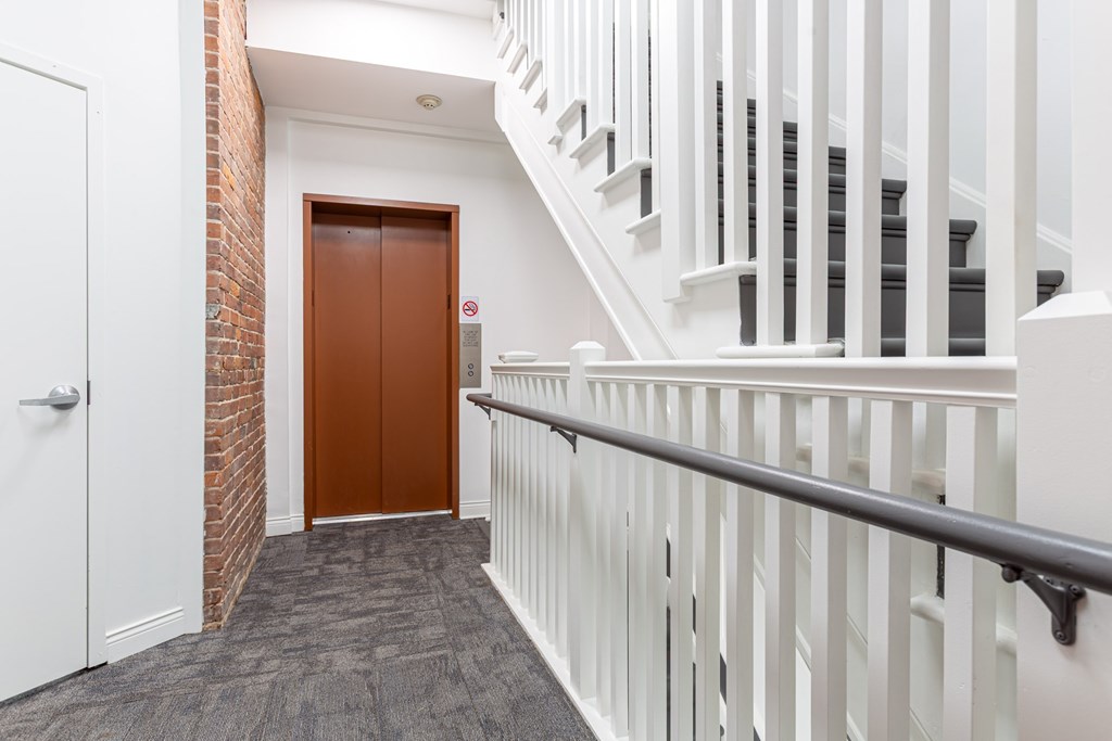 A hallway with a white railing and a brown door.