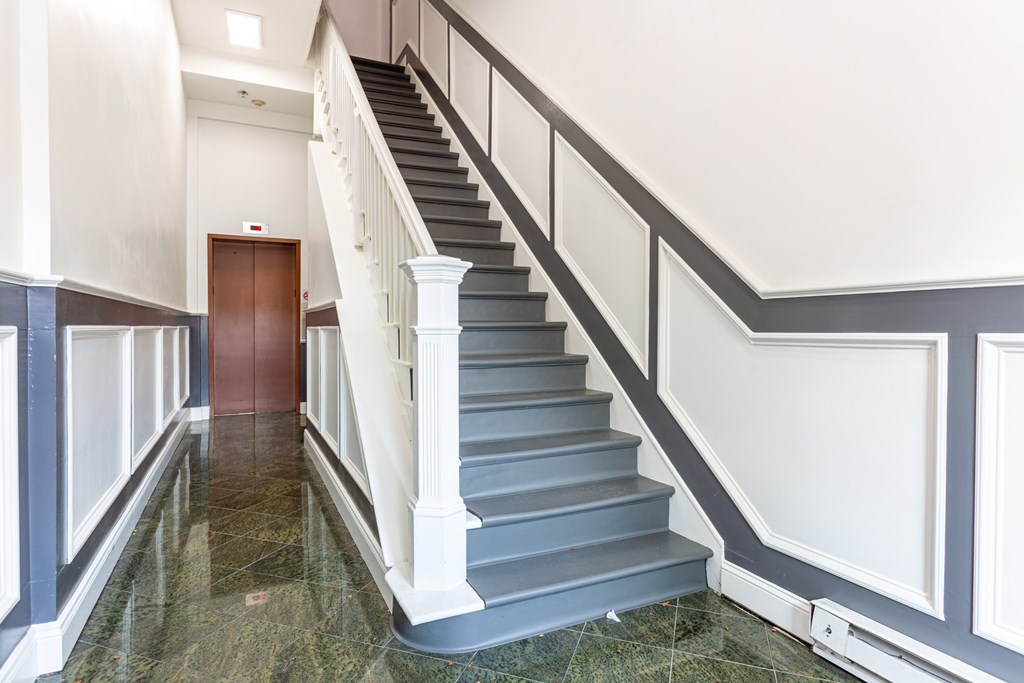 A staircase with a wooden handrail and a marble floor.