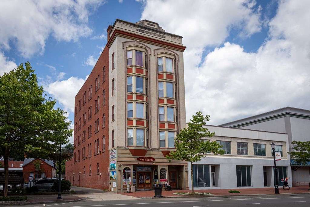 A tall red brick building with a white trim and a red awning on the front.