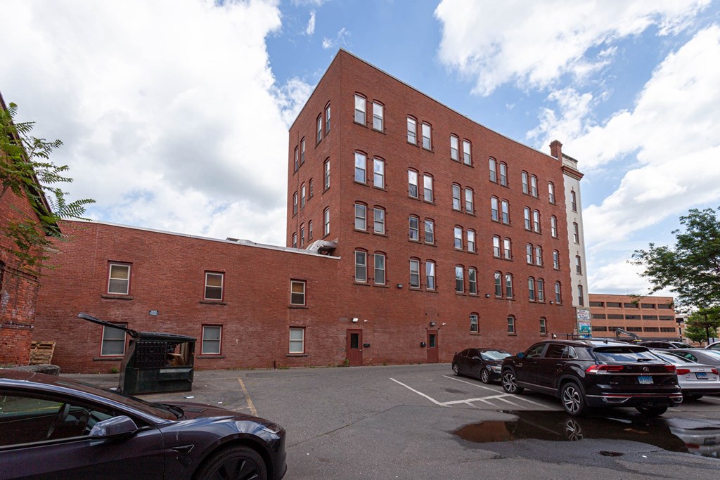 A parking lot with cars and a red brick building.