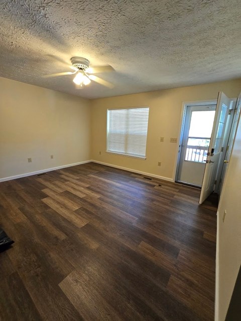 an empty living room with a hard wood floor and a door