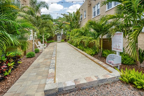 a walkway with palm trees and a sign in front of a building