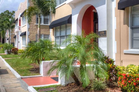 a building with a red door and palm trees in front of it