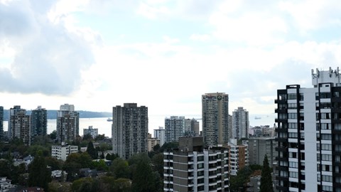 A cityscape with tall buildings and a cloudy sky.