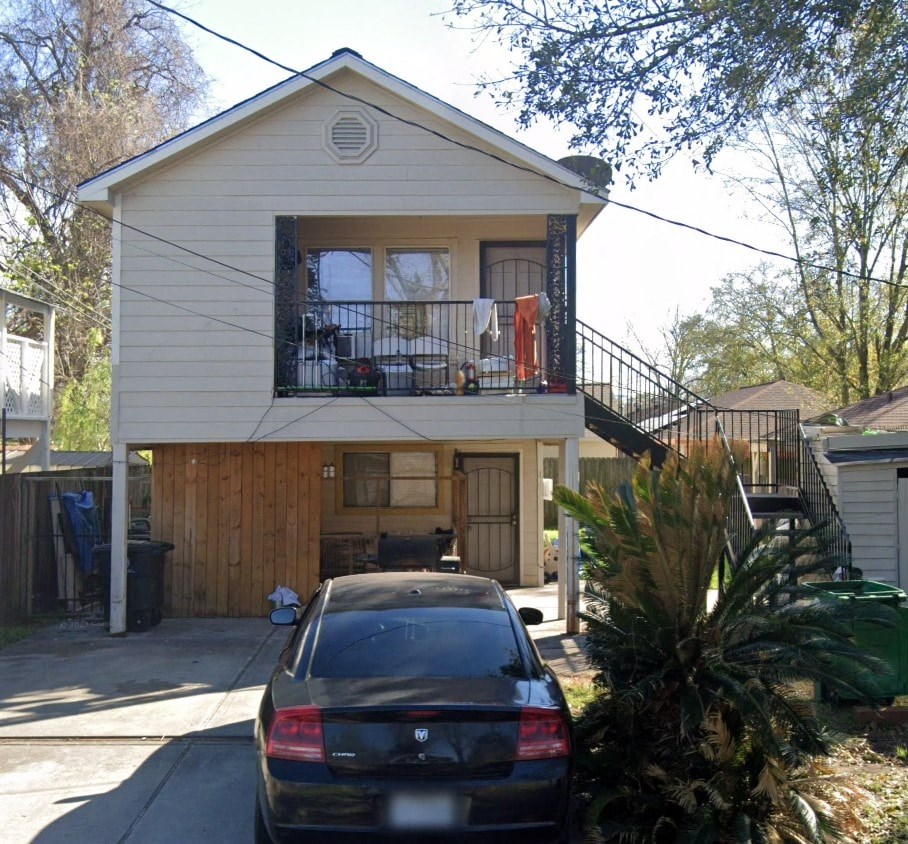 A black car is parked in front of a two-story house.