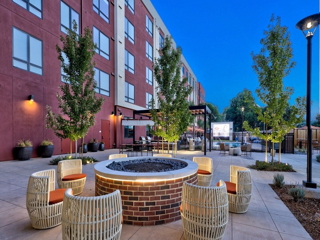 a courtyard with a fire pit and chairs in front of a building