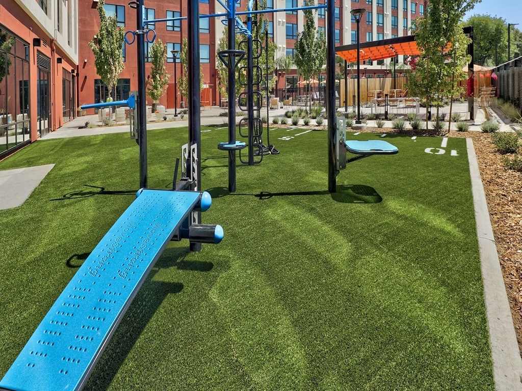 a fitness center with a blue bench and weights on the grass