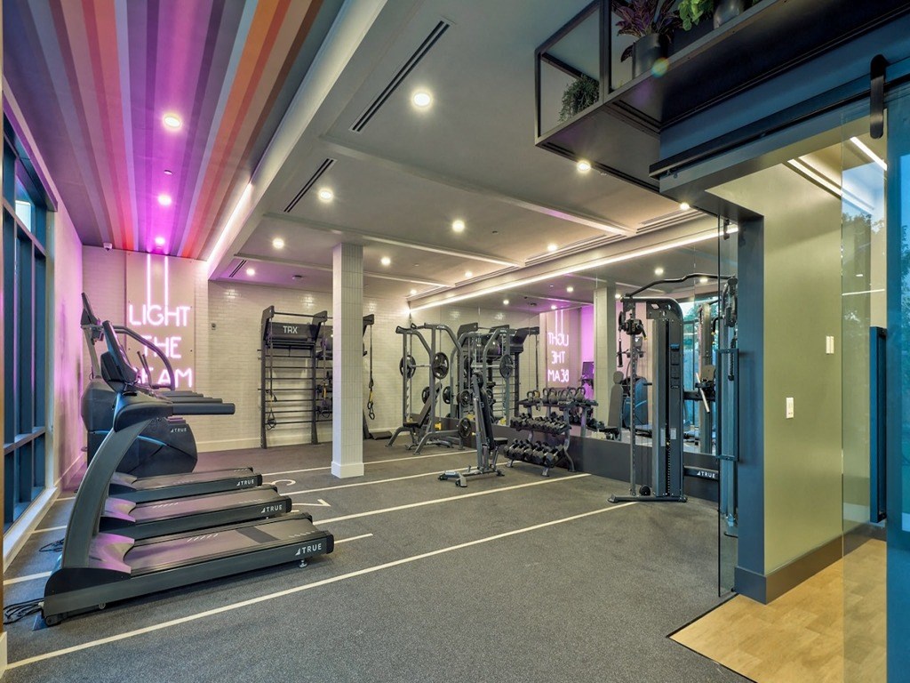 a gym with treadmills and other exercise equipment in a building with purple lighting