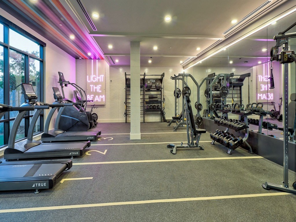 a gym with weights and cardio equipment and a large window
