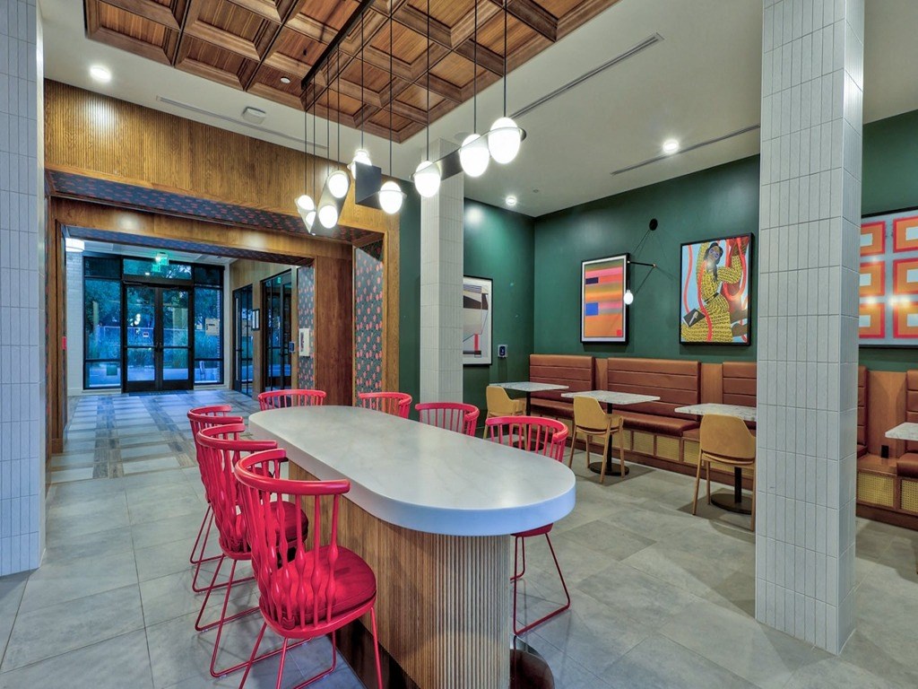 a communal table in the lobby of a restaurant with red chairs