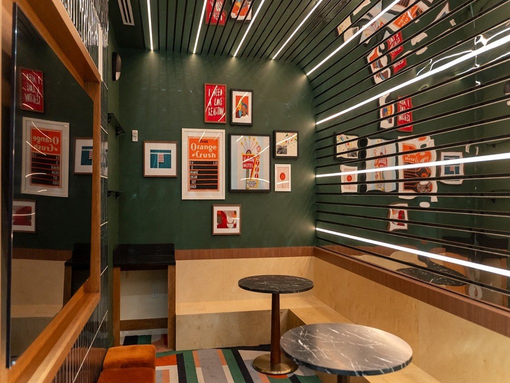 a seating area with a table and a green wall with posters