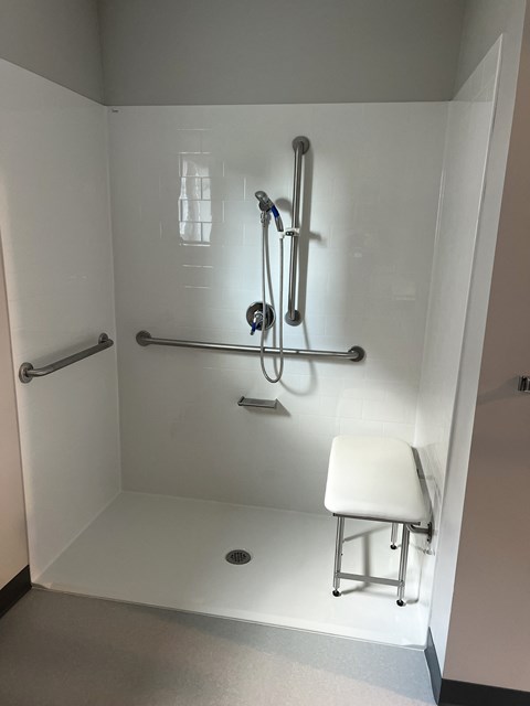 A white shower stall with a shower head and hand held shower.