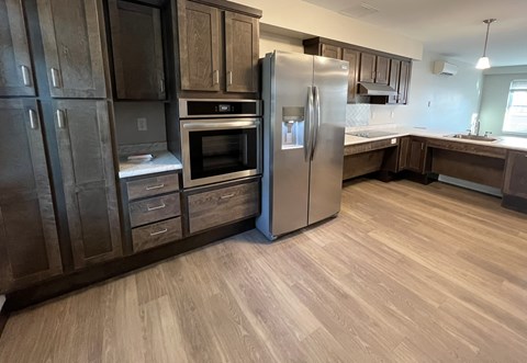 A kitchen with a refrigerator, oven, and cabinets.
